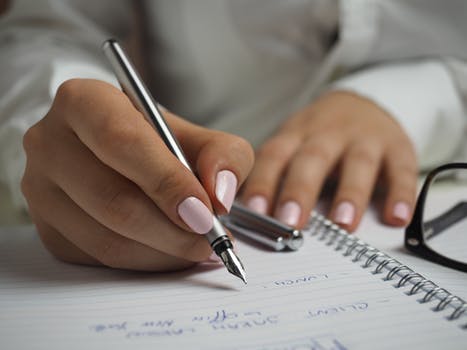 hands writing with a pen and paper